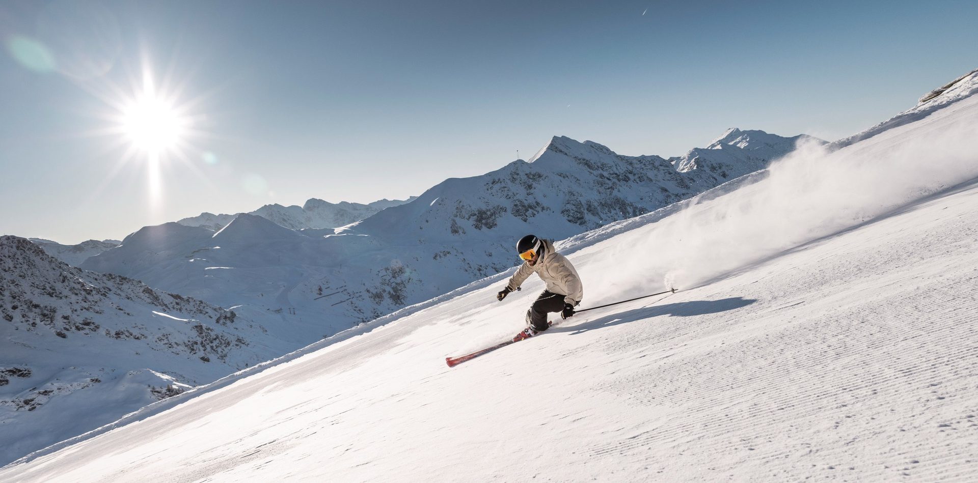 Skiër aan het carven op een geprepareerde piste in Obertauern in de zon